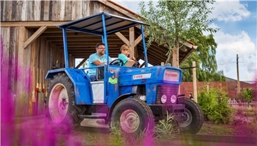Ein Mann und ein kleiner Junge fahren auf einem blauen Traktor.