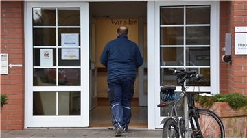 Das Foto zeigt einen Mann, wie er in das Pflegeheim geht. 