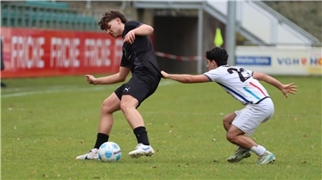 Zwei junge Männer in Sporttrikots kämpfen um einen Ball.
