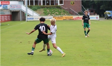 Zwei Jungen kämpfen auf eine Rasen um einen Fußball.
