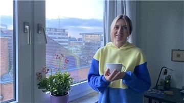 Eine Frau steht vor einem Fenster. 