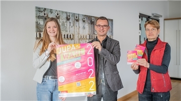 Drei Menschen halten Werbung für das Jugendparlament in die Kamera.