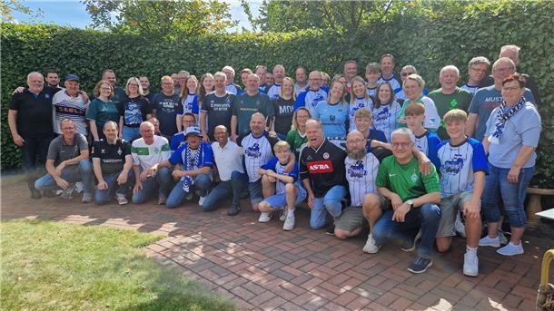 Eine Gruppe Erwachsener und Kinder lächelt in die Kamera.