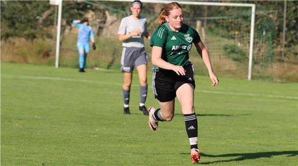 Eine Frau im Trikot läuft über Rasen.