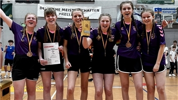 Drei Mädchen haben Medaillen um den Hals und jubeln in die Kamera.