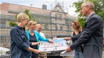 Die Wulsdorfer Fichteschule in Bremerhaven wird rundum innen und außen energetisch saniert. Während der großen Ferien wird mit der neuen Fassade begonnen, zeigen (von links) Architektin Tanja Schmitz und Isabelle Bornemann von Seestadt-Immobilien, Ingenieur Eugen Rukaber, Astrid Milch (CDU) und Betriebsleiter Holger Schneeberg.
