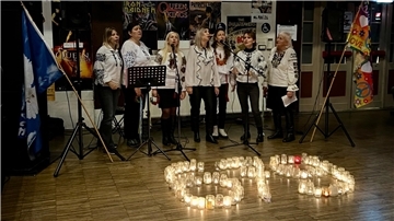 Frauen singen in einem Kulturzentrum Lieder, während vor ihnen - mit Teelichtern gebildet -die Zahl 679 zu sehen ist.