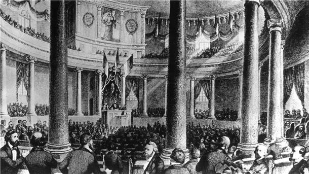 Die zeitgenössische Darstellung zeigt die erste Sitzung der Nationalversammlung, die von ihrem Präsidenten Heinrich von Gagern am 18. Mai 1848 in der Frankfurter Paulskirche eröffnet wurde.