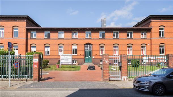 Tafel-Schließung in Bremerhaven: Das Gebäude ist nicht das Problem rotes Backsteingebäude mit grüner Tür in einer parkähnlichen Anlage hinter einem Zaun