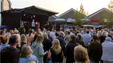 Große Menschenmenge vor einer Open-Air-Bühne im Abendlicht, auf der eine Band live beim Langener Ortsgemeinschaftsfest spielt.