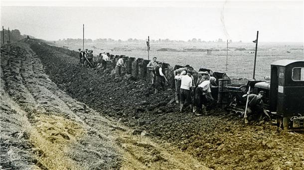 Wesermarsch: Deichbau war hier schon immer harte Arbeit Männer holen mit Schippen Erde aus den Loren einer kleinen Bahn
