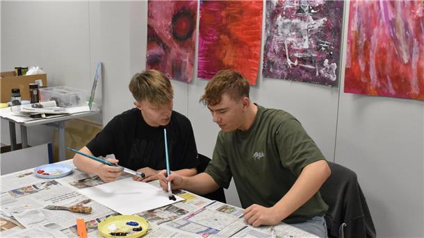 Kooperation zweier Schulen: Jetzt hat der Zevener Bildungsweg neue Räume Zwei junge Männer malen mit Pinseln auf einem Blatt Papier