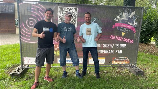 Das sind die wichtigsten Infos zum Villagemove Festival in Nordenham Drei Männer vor einem Festivalplakat.