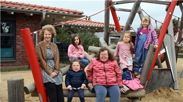 Das Foto zeigt die drei Praktikantinnen mit Kindergartenkindern. 