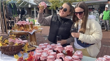 Zwei Frauen schauen sich Gläser mit Marmelade an.