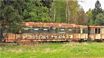 Eine alte Straßenbahn rostet auf einem Abstellgleis. 