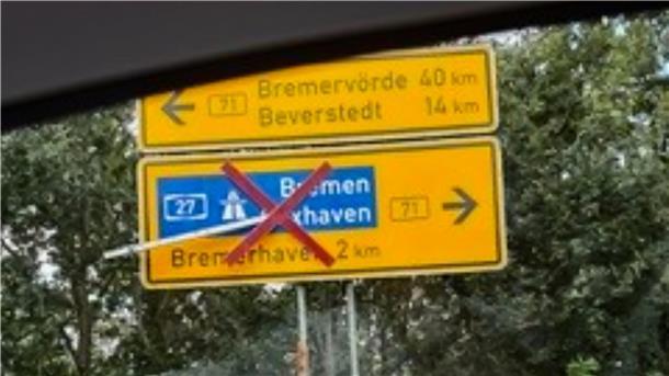 Ein gelb-schwarzes Schild, auf dem die Begriffe "Bremerhaven", "Beverstedt" und "Bremervörde" stehen. Über den Abschnitt "Bremerhaven" ist ein rotes Kreuz gelegt.
