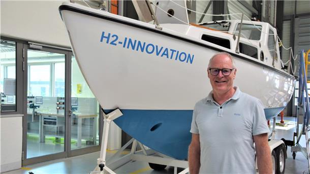 Dieter Sichau steht vor einem Motorsegelboot.