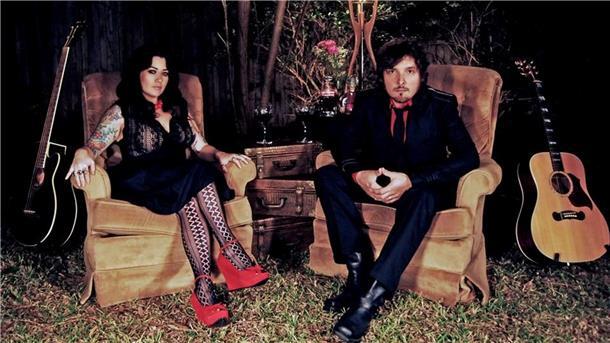 Von Texas nach Bremerhaven: Division Men live im Doppelkonzert Das US-Duo Division Men sitzt in Sesseln im Freien, flankiert von zwei Gitarren. Beide blicken ernst in die Kamera, die Szene wirkt atmosphärisch und künstlerisch inszeniert.