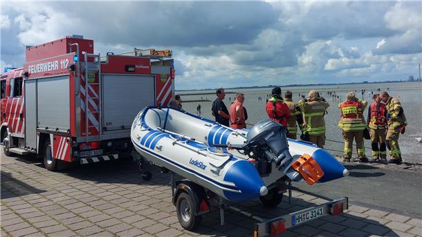 Feuerwehr und DLRG retten Urlauber und zwei Hunde im Watt vor Tossens Bild mit einem Feuerwehrauto, einem Schlauchboot und Einsatzkräften von Feuerwehr und DLRG am Watt vor dem Friesenstrand Tossens.