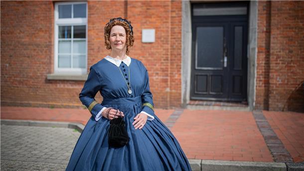 Frau in historischem Kostüm vor altem Haus