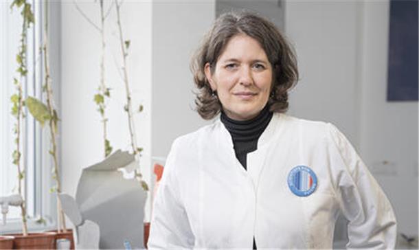 Frau in weißem Kittel vor Plastikmüll