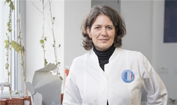 Frau in weißem Kittel vor Plastikmüll