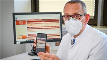 Dr. Michael Sachse zeigt auf dem Handy die App, mit deren Hilfe Kontakt zu weiter entfernt wohnenden Patienten gehalten werden kann.