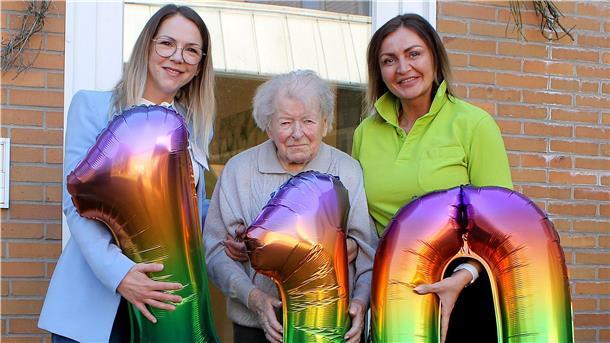 Drei „110-Luftballons“ werden Jubilarin Ingeborg Fründt von OsteMed-Einrichtungsleiterin Melina Kies (links) und der Zevener Tagespflege-Leiterin Monika Lippold (rechts) überreicht.