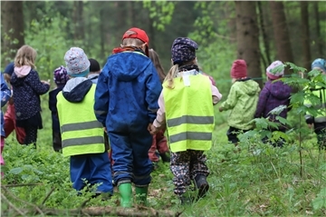 Kinder gehen durch einen Wald.