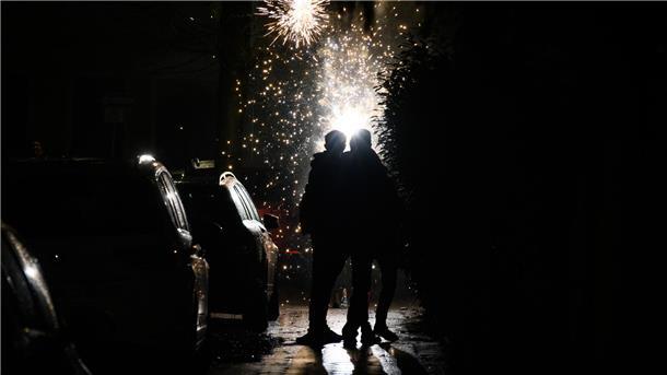 Zisch, Boom, Bang! Das sollten Sie vor der Silvesternacht wissen Menschen zünden auf einer Straße in der Dunkelheit Feuerwerkskörper.