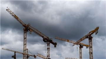 Dunkle Wolken ziehen über die Kräne auf einer Baustelle. „Alle Indikatoren am Bau zeigen deutlich nach unten, eine Trendwende ist nicht in Sicht“, stellt die Bauindustrie fest.