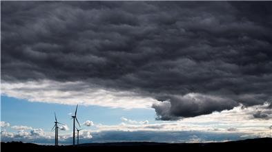 Dunkle Wolken ziehen über Windräder hinweg. Sturm droht, das heißt viel wind, aber deswegen nicht unbedingt mehr Strom.