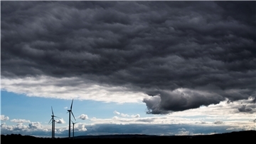 Dunkle Wolken ziehen über Windräder hinweg. Sturm droht, das heißt viel wind, aber deswegen nicht unbedingt mehr Strom.