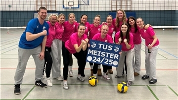 Eine Mannschaft aus jungen Frauen im pinken Shirt schaut lachend in die Kamera. 