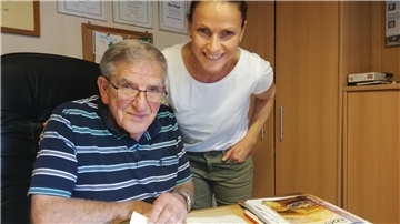 Ein Mann mit Brille und eine Frau mit weißem Shirt im Büro.
