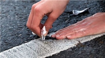 Ein Aktivist von „Letzte Generation“ klebt seine Hand mit Sekundenkleber auf der Straße in Berlin während einer Sitzblockade fest.