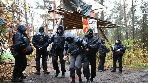 Ein Aktivist wird von Polizisten aus dem Protestcamp in der Nähe des Tesla-Autowerks in Grünheide abgeführt.
