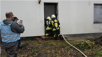 Ein Angriffstrupp unter Atemschutz verschafft sich Zugang zu dem Gebäude - unter den kritischen Augen der Übungsbeobachter.