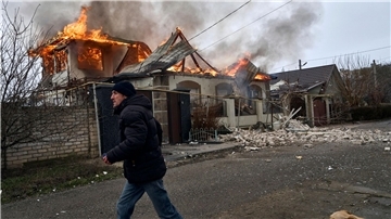 Ein Anwohner läuft an einem brennenden Haus in Cherson vorbei, das nach ukrainischen Angaben bei russischem Beschuss am orthodoxen Weihnachtsabend getroffen wurde.