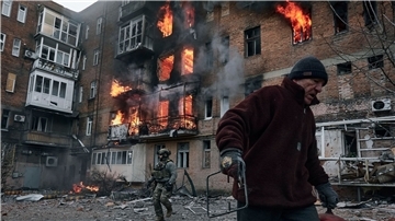 Ein Anwohner verlässt in Bachmut sein Wohnhaus, das nach einem Beschuss in Flammen steht.