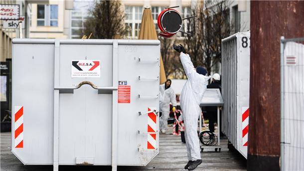 Aufräumen nach Platzen des Aquariums - Ursachensuche läuft Ein Arbeiter wirft einen Stuhl in einen Container.
