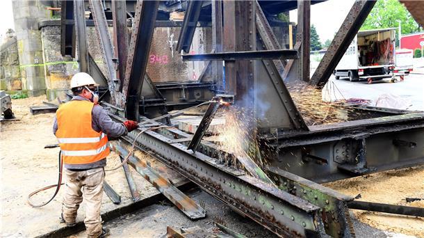 Bremerhavener Eisenbahnbrücke in Stücke zerlegt Ein Arbeiter zerlegt die Stahlkonstruktion mit einem Schneidbrenner.