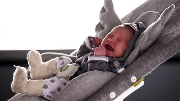 Warum manche Babys mehr schreien Ein Baby liegt in einer Kinderwippe und schreit.