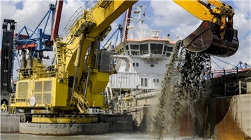 Ein Bagger baggert Schlick aus der Elbe.