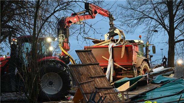 Abrissbagger in Lützerath - Widerstand bröckelt Ein Bagger lädt in Lützerath Reste von Hütten  auf einen Lkw.