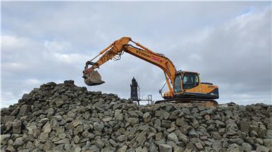 Ein Bagger schichtet Wasserbausteine auf der Leuchtturmwiese in Dorum-Neufeld auf. Das Material soll im kommenden Frühjahr verbaut werden.