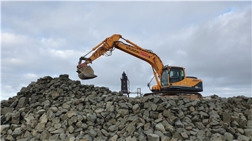 Ein Bagger schichtet Wasserbausteine auf der Leuchtturmwiese in Dorum-Neufeld auf. Das Material soll im kommenden Frühjahr verbaut werden.