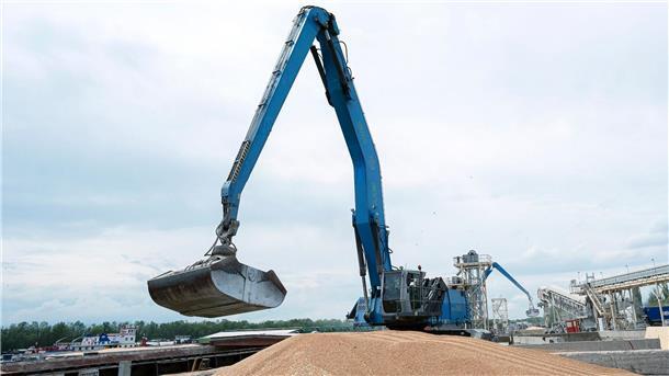 Ein Bagger verlädt in einem Getreidehafen Getreide in ein Frachtschiff.