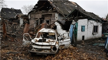 Ein beschädigtes Auto aus der Sowjet-Ära der Marke Saporoshez ist neben einem zerstörten Wohnhaus zu sehen.
